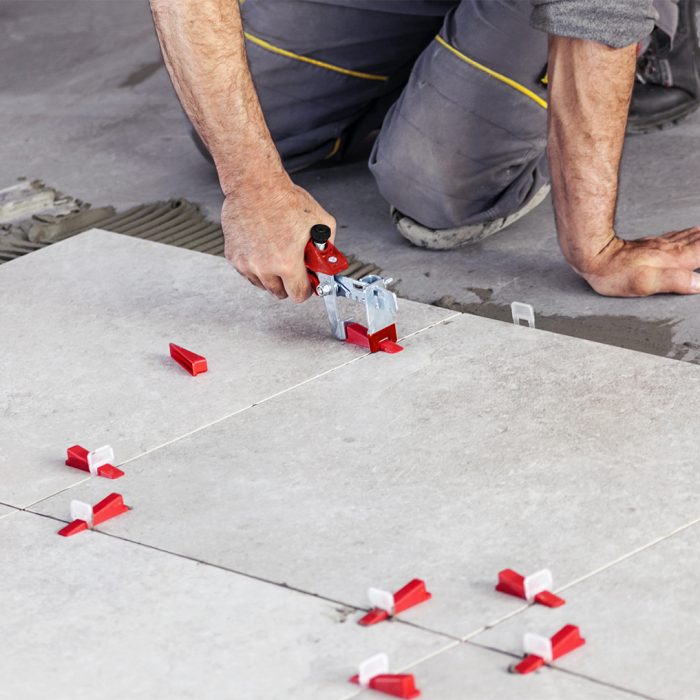 Ceramic Tiles. Tiler placing ceramic wall tile in position over